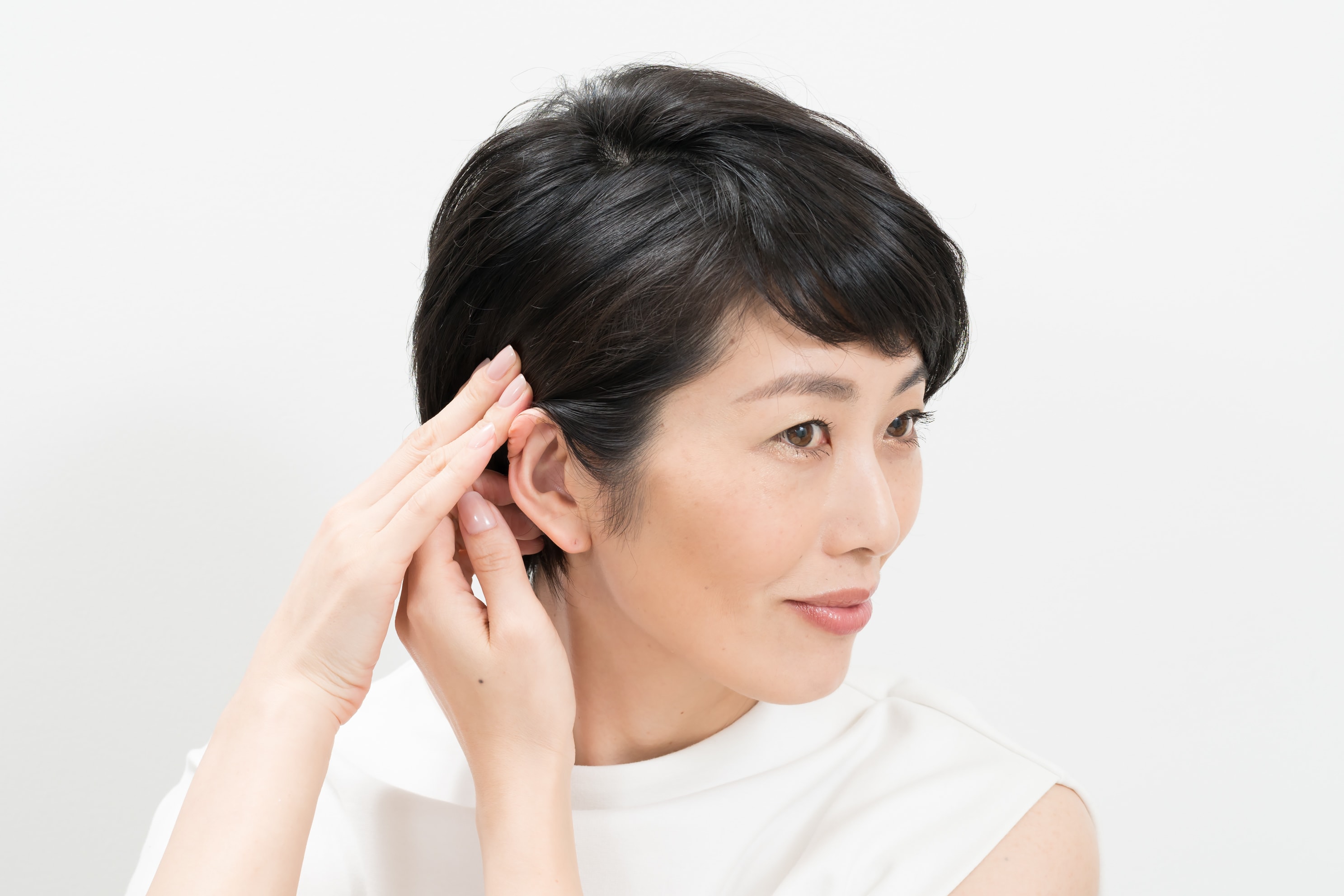短い方の髪をなで付けるようにして耳にかけます。