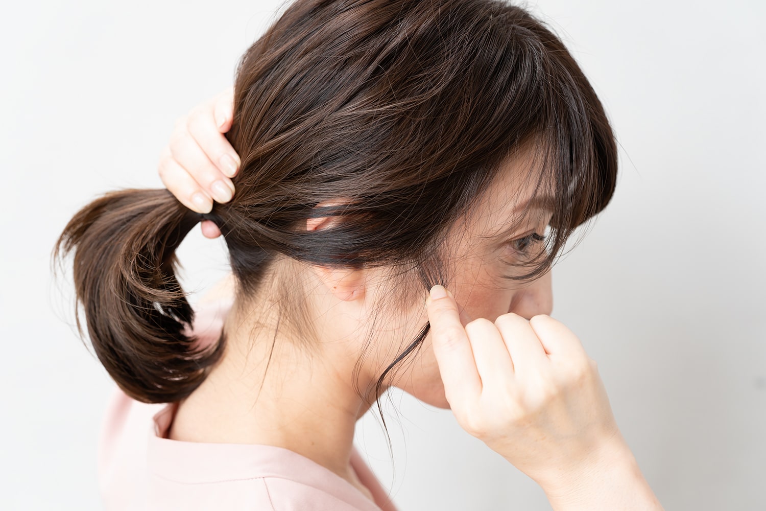髪をまとめる時は手グシでザックリと。耳は半分だけ隠すのがポイント! 後れ毛はもみあげの少し上を、ひとつまみだけ引き出して。