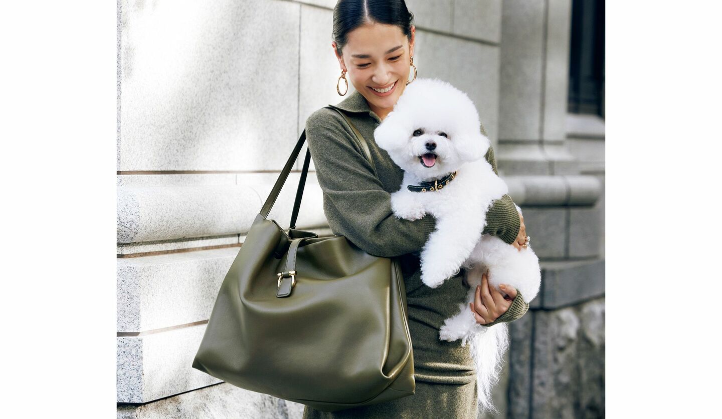 フェラガモのトートバッグと白い犬を抱えたモデル