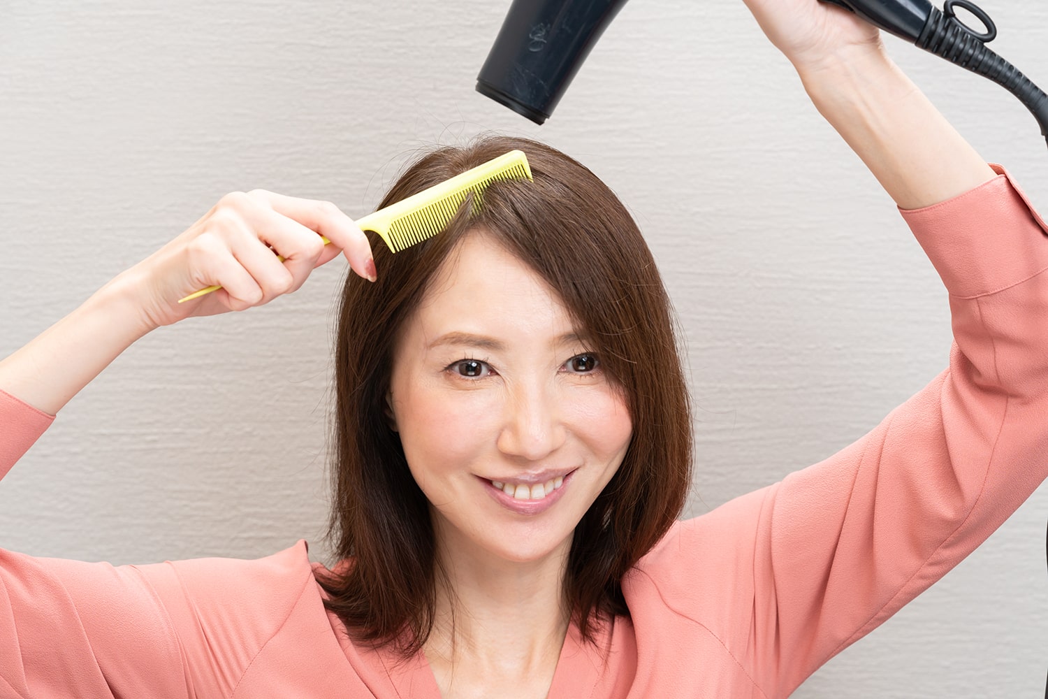 このときもドライヤーは真上から。なで付けたい方向にクシでとかすこと。
