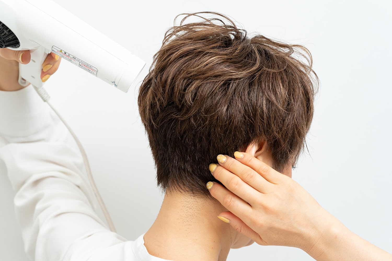 最後にドライヤーの熱を当てながら襟足を抑えて完成。