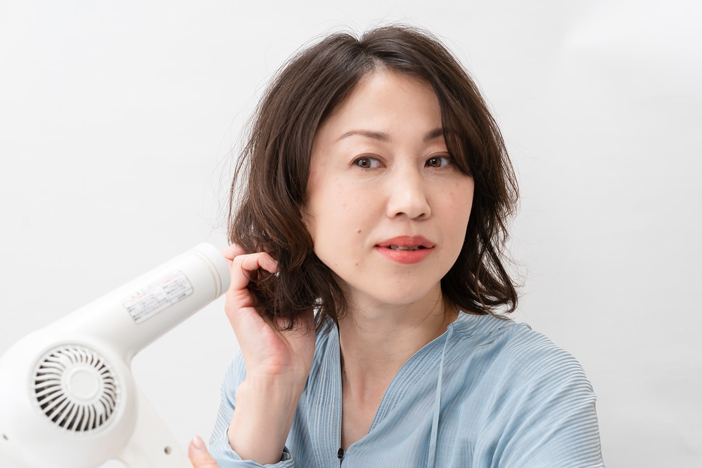 ドライヤーは弱風。毛束を握らず、毛先を支える程度に持ちながら風をあてる。