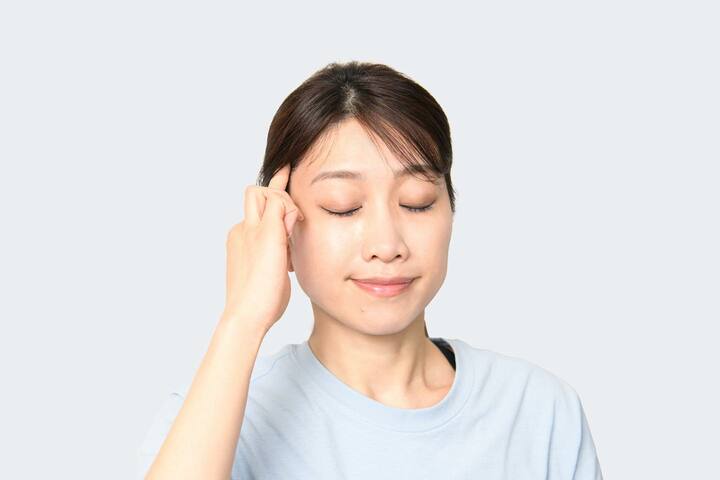 右手の人差し指、中指を側頭筋に置き、軽く引き上げる