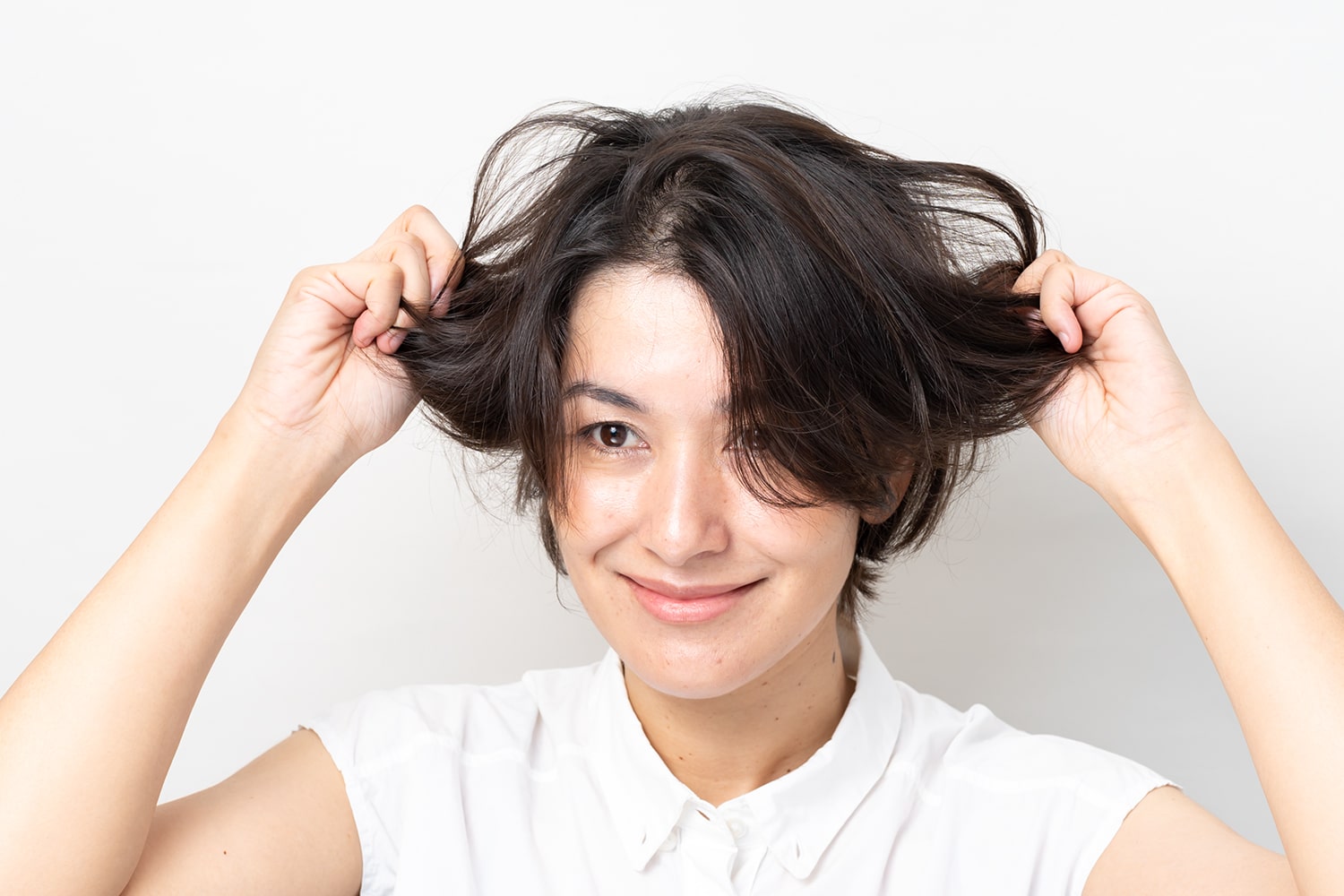 両手のひらにワックスを広げ、髪を握るようにしてなじませる。