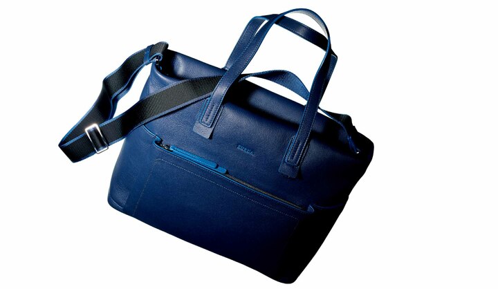 メンズアイテムだがパートナーと一緒に使えるような、少し小ぶりのサイズも特徴。鮮やかなブルーをあしらったコバ部分のパイピングも洒落ている。［名品データ］●モデル名：『イカロ』 素材：牛革 ●サイズ：縦21×横36×マチ12.7cm 色展開：写真のネイビーのほか、ブラックがあり ￥80,000（フルラ ジャパン）※税抜、参考価格