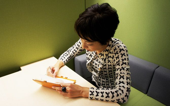 エルメスのオレンジの手帳に書き込む吉川純さん