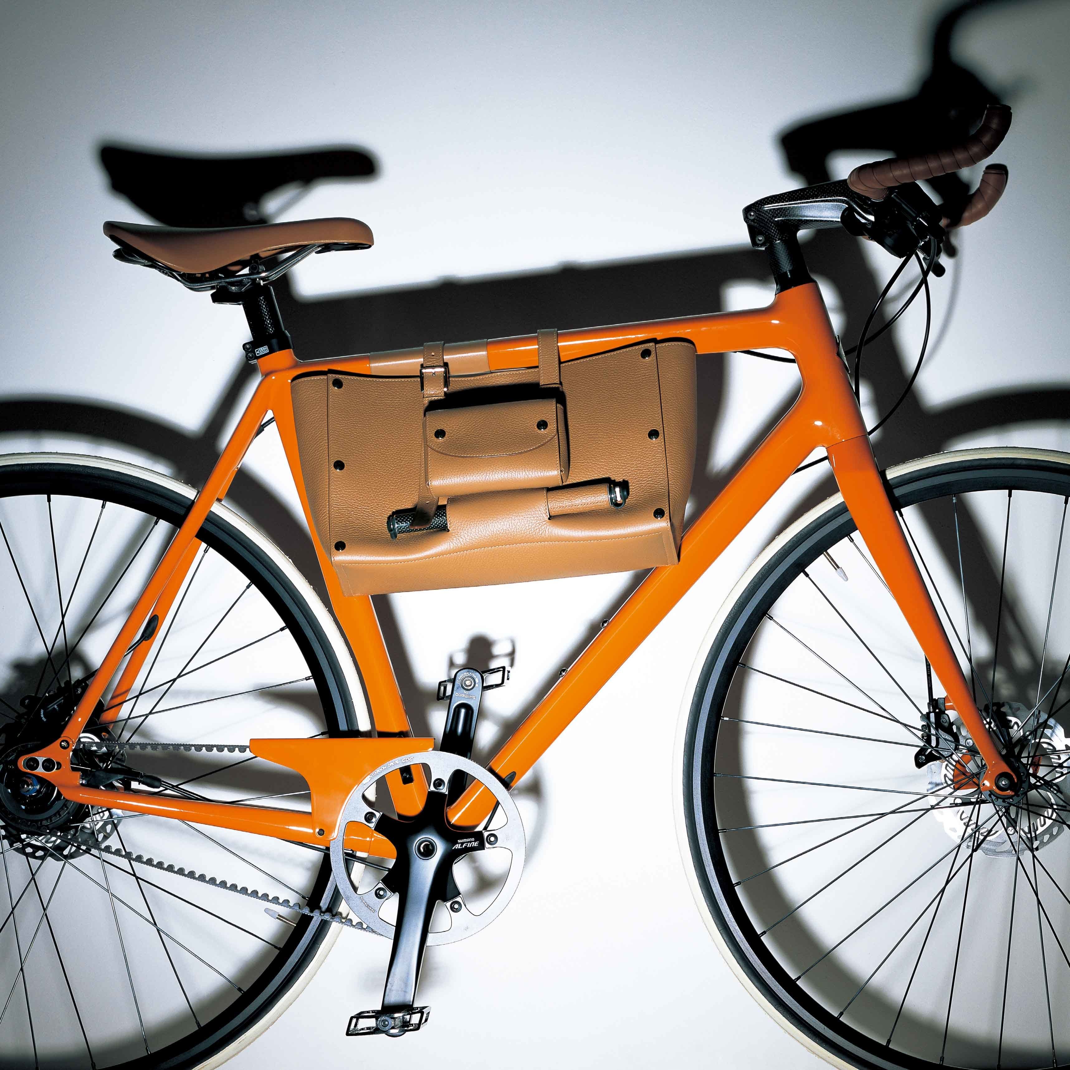 写真のスポーツタイプの自転車は、2015年の新作。シティタイプもあり。各3サイズ展開。ベースのフレームは、オレンジのほか、ホワイトとブラックの全3色を用意。すべて一部店舗のみで購入可能(要問い合わせ)。自転車『ル・フラヌール・スポルティフ・ドゥ・エルメス』¥1,660,000・サドルバッグ¥486,000・サドルバッグの中央に装着したツールバッグ¥109,000※工具付き(エルメスジャポン)