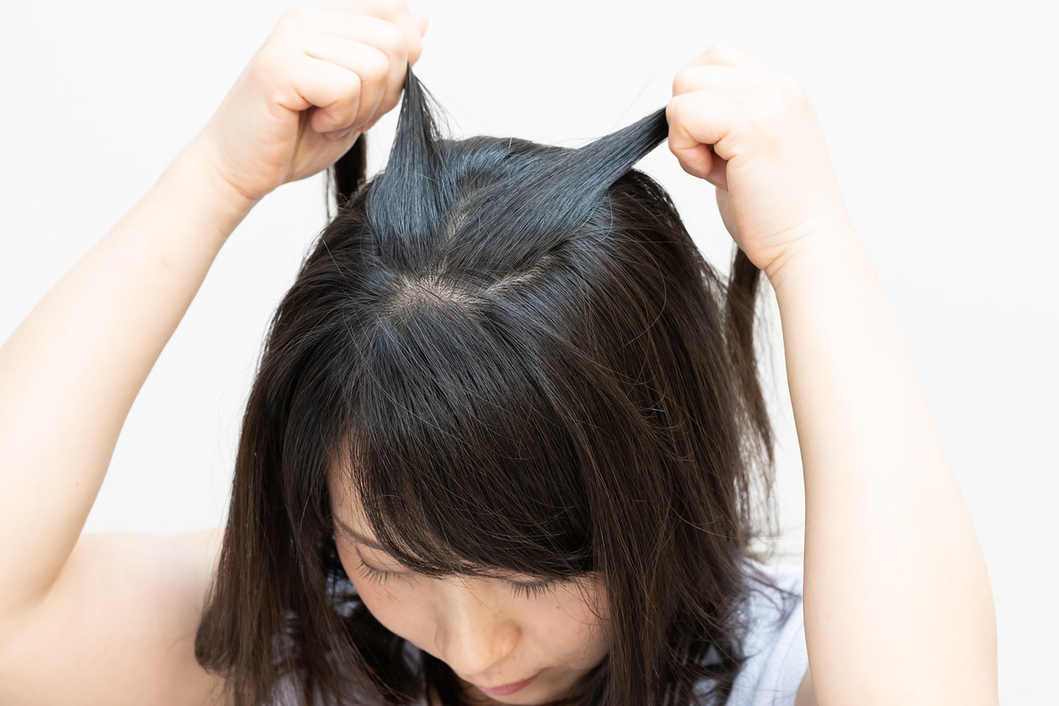 直径5㎝を目安に頭頂部の狭い範囲の毛束とり、それぞれの手に毛束を持つ。