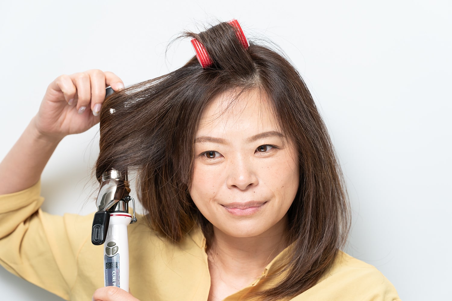 コテは32mmを使用。耳前の毛束を外巻きに。毛束の中間から毛先までしっかりと巻いて。逆サイドも同様に。