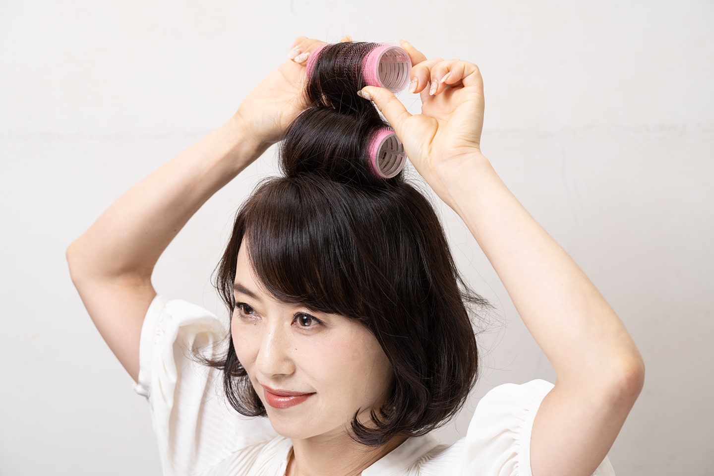毛束を持ち上げ、根元を立たせるように毛先から根元まで後ろ向きに巻く。