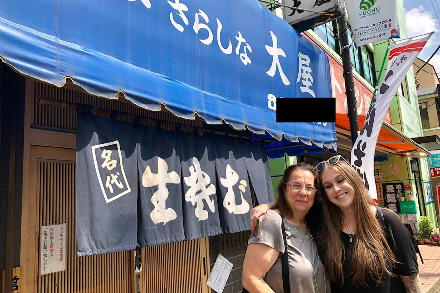 お蕎麦屋さんの前で写真を撮る女性