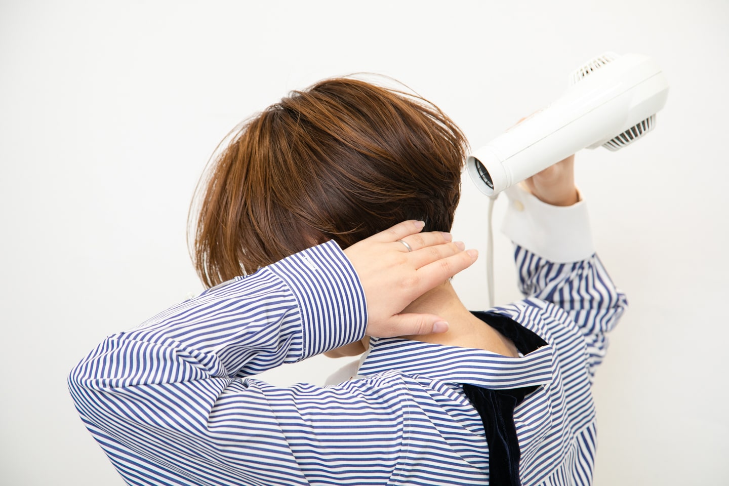 襟足は、手で押さえながらドライヤーの風を上から当てて、ボリュームが出ないように乾かす。