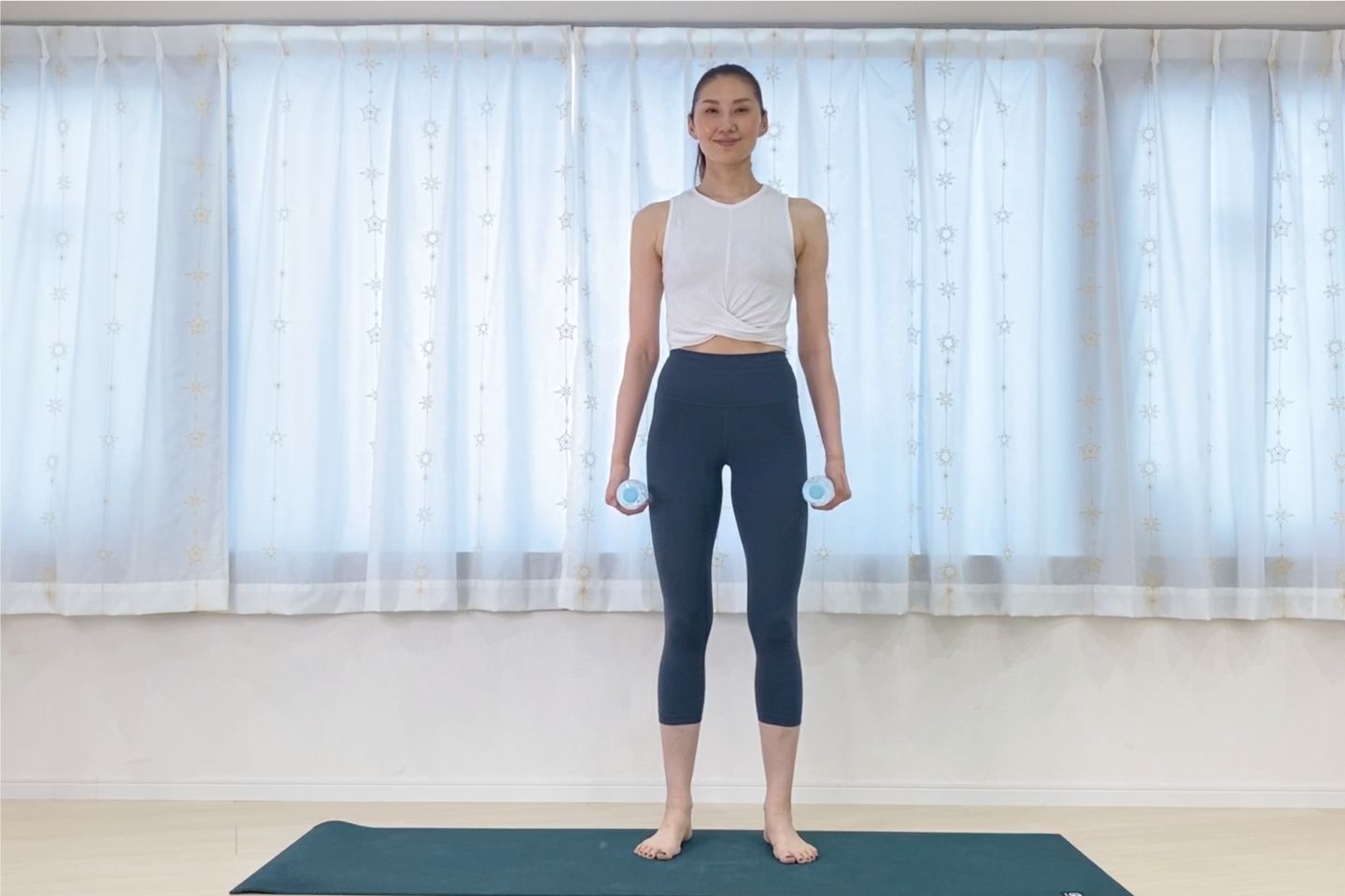 両手にペットボトルもしくはダンベルを持ち、脚を腰幅に開き、まっすぐに立ちます。