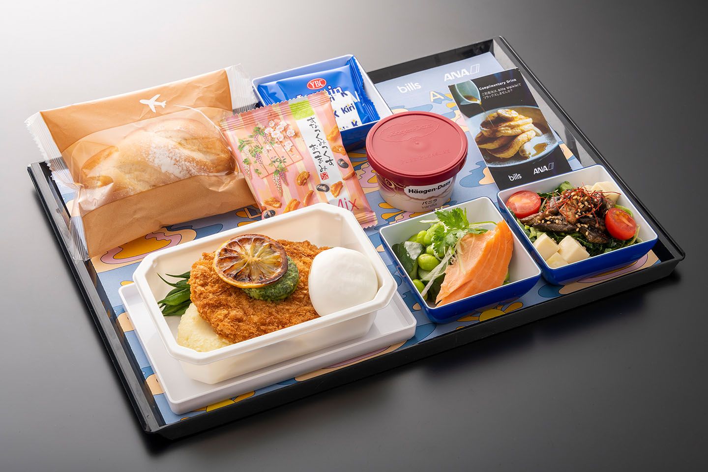 機内食1のメインは「ポークシュニッツェル マッシュポテト、ポーチドエッグ、パセリとケッパーバターを添えて」。提供期間は2019年5月24日(金)〜8月31日(土)、2019年12月1日(日)〜2020年2月29日(土)。