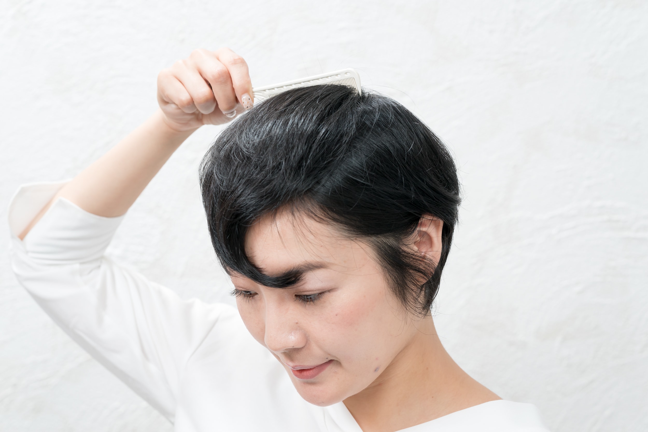 つむじより少し前にある毛束をクシで前に持ってくる。前髪を増やすようなイメージで。