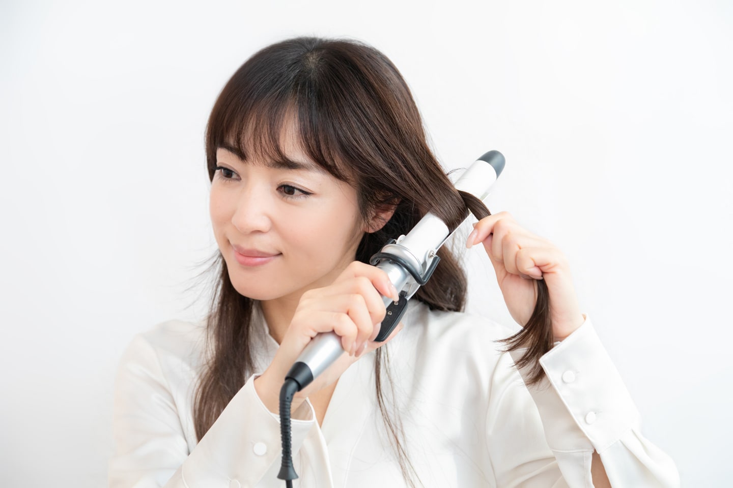 32mmのヘアアイロンを使用。髪の中間からアイロンに巻きつけ、少し置いたら毛束を外して毛先まで滑らせる。