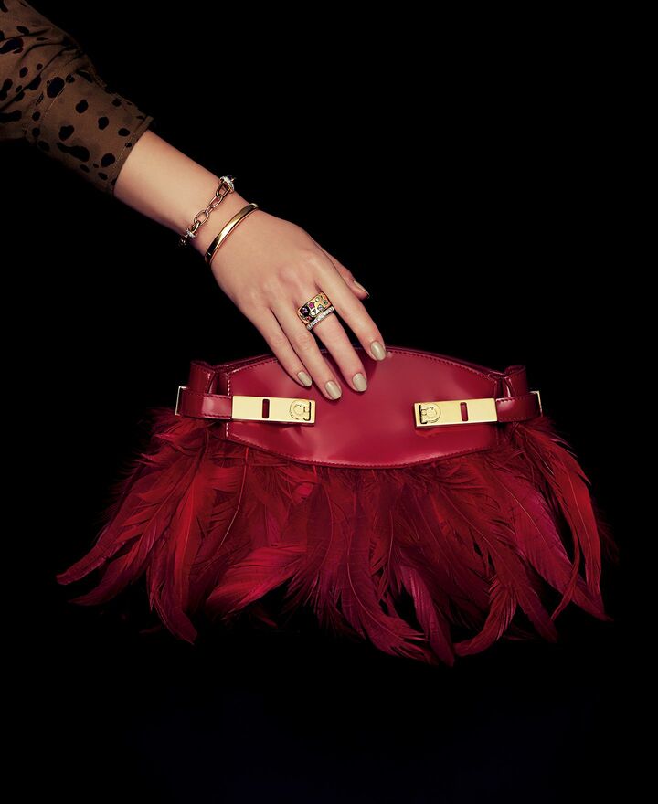 「フェラガモ」のバッグと「ポメラート」のジュエリーを纏った女性の手元