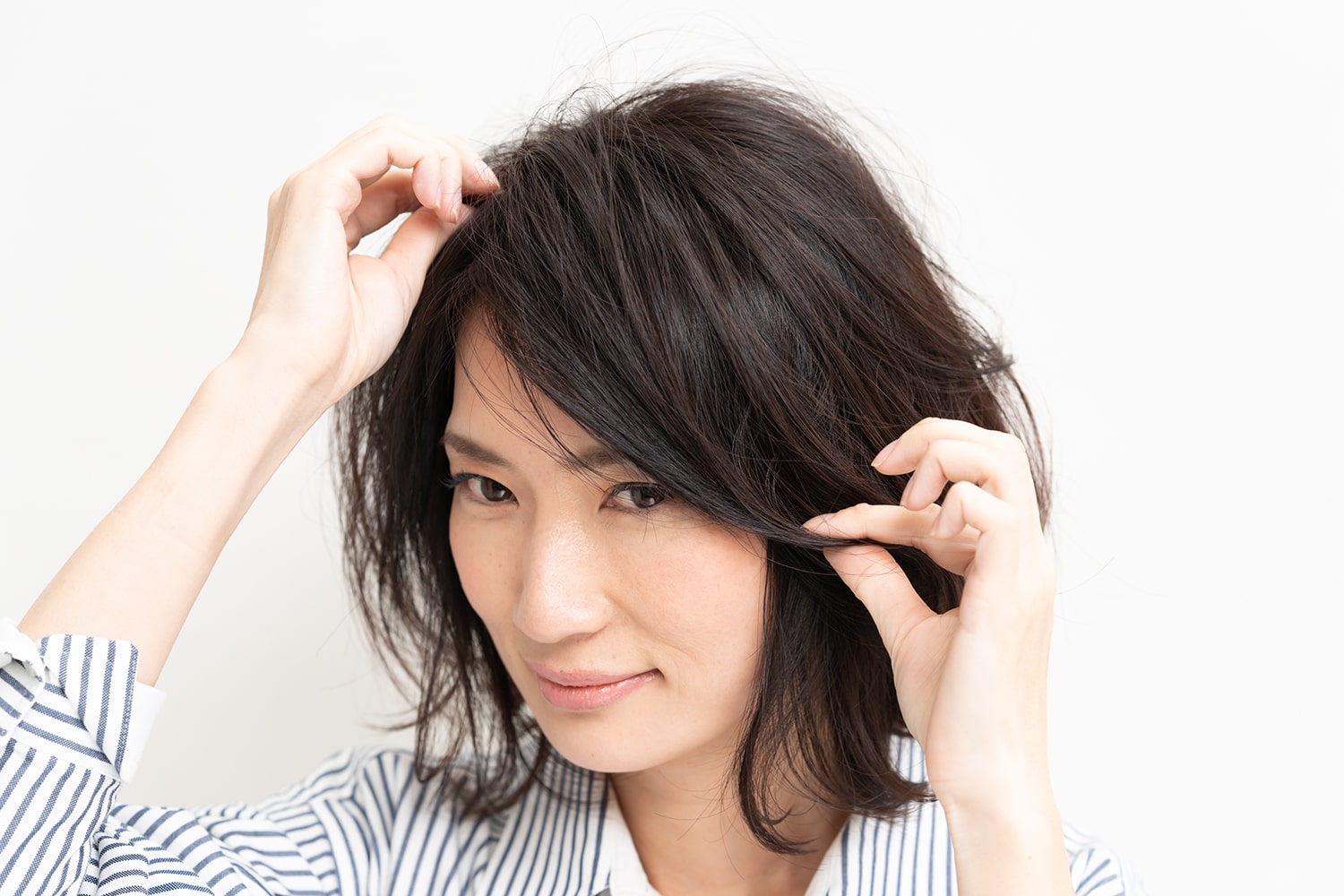 鏡を見ながら全体のシルエットを整える。とかすのではなく、指でつまんで束感を作るようなイメージで。