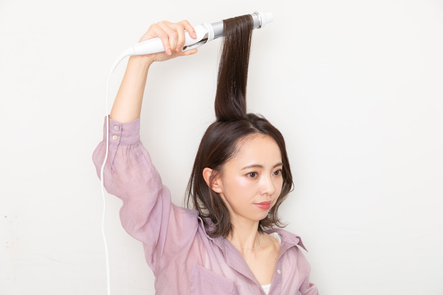 トップの髪を真上に引き出して、毛先を一回転巻く。