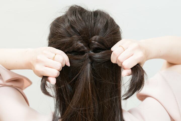 「くるりんぱ」をした根元を締めるように、サイドの髪を束ねた毛束だけを左右に引っ張る。