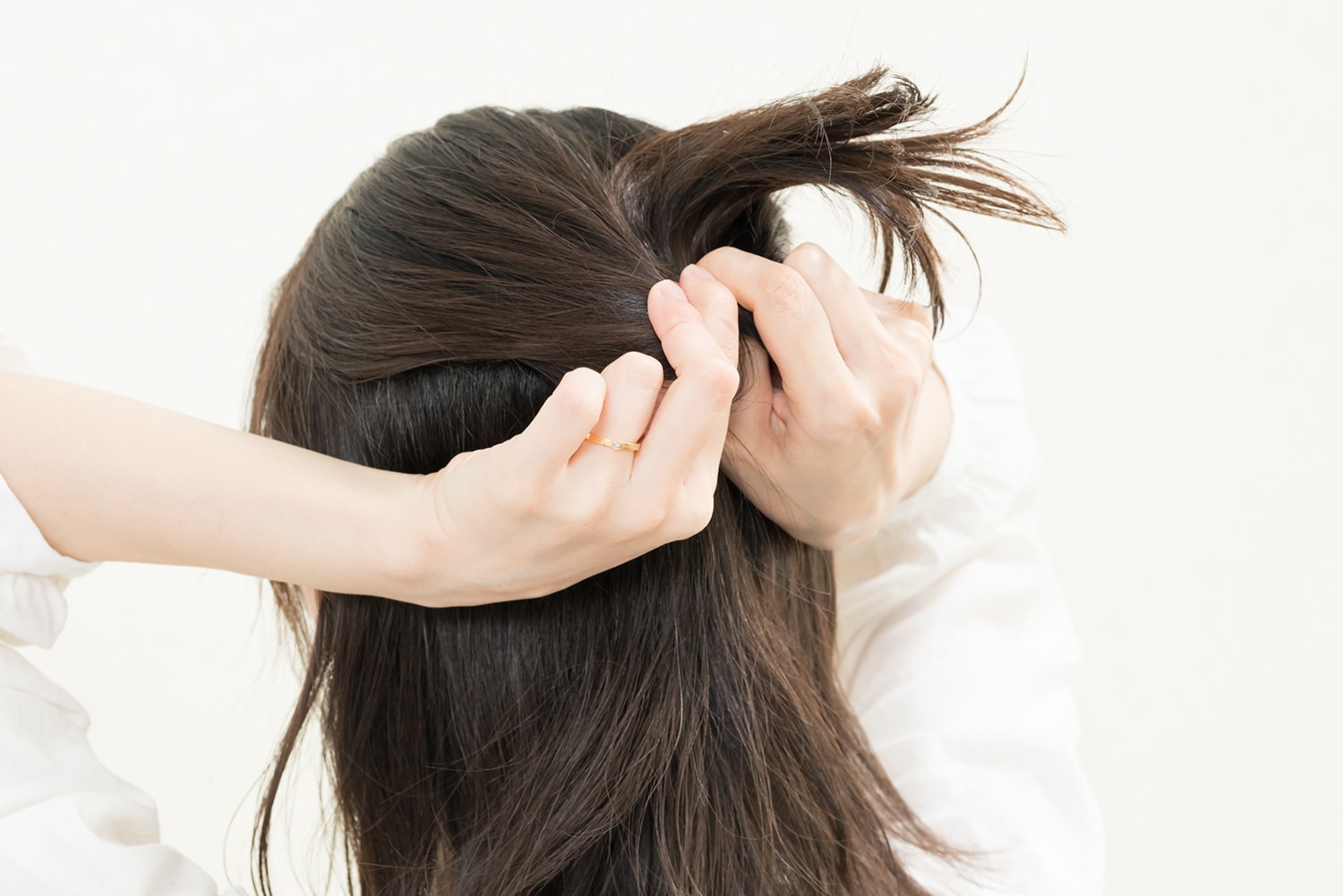 結んだ髪の上を割いて上から通す。その後、頭頂部の髪をつまんで高さを出す。