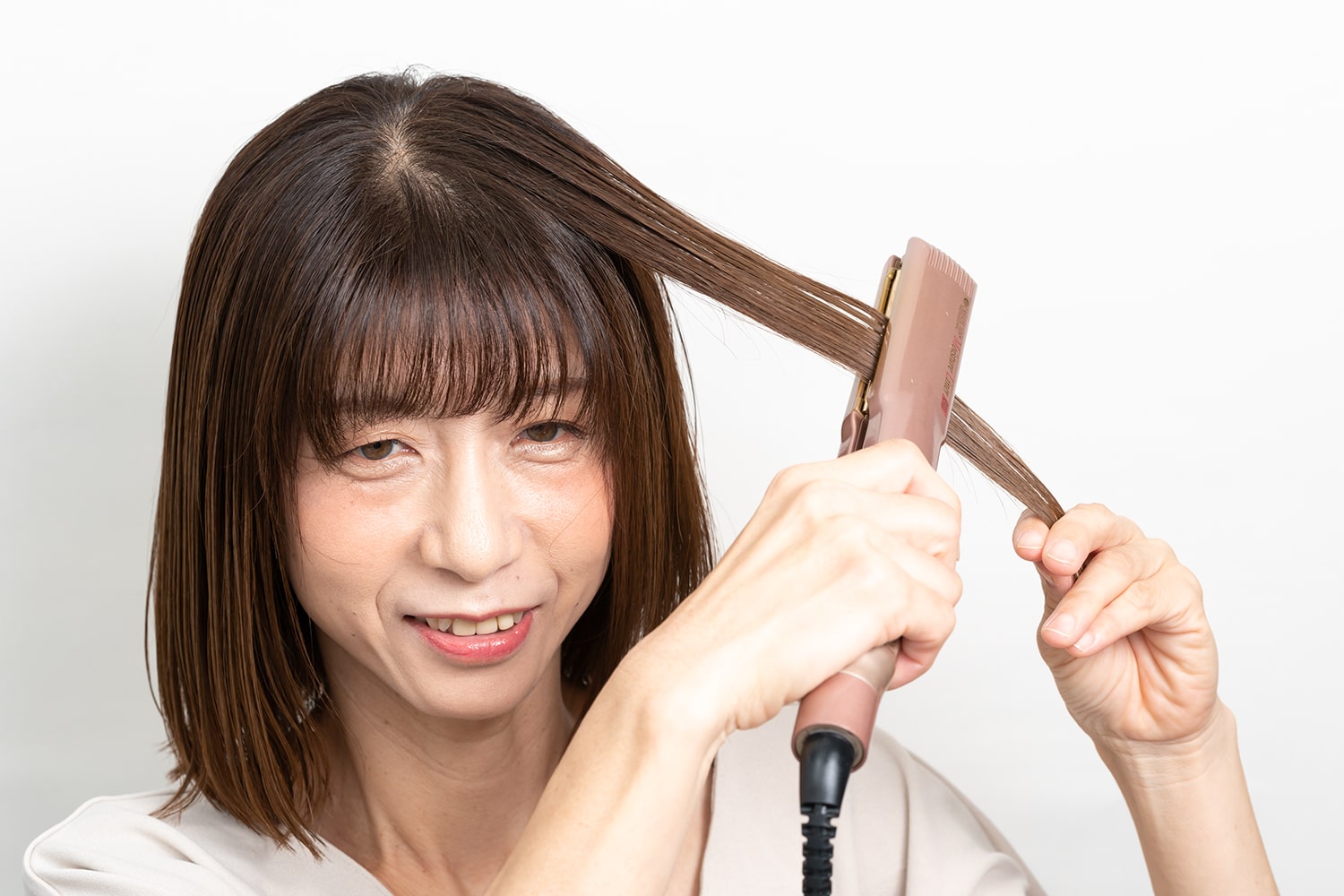 髪の表面に熱を与えてツヤを出す。根元から毛先にかけてアイロンをすべらせて。