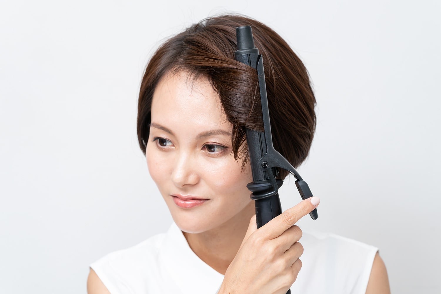 コテは25mmを使用。前髪、顔まわり、サイド、後頭部の順にすべてリバース巻きに。毛束の中間を巻きながら毛先に向けてコテをすべらせるように動かして。