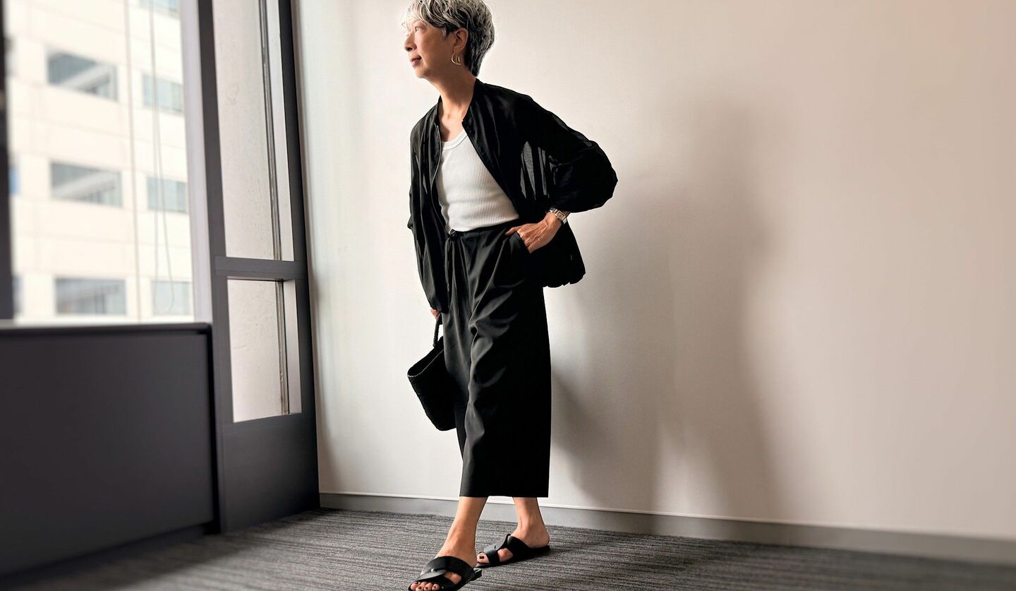 透ける黒のブルゾンに白のタンクトップ、黒パンツ、黒サンダルを合わせたコーディネート