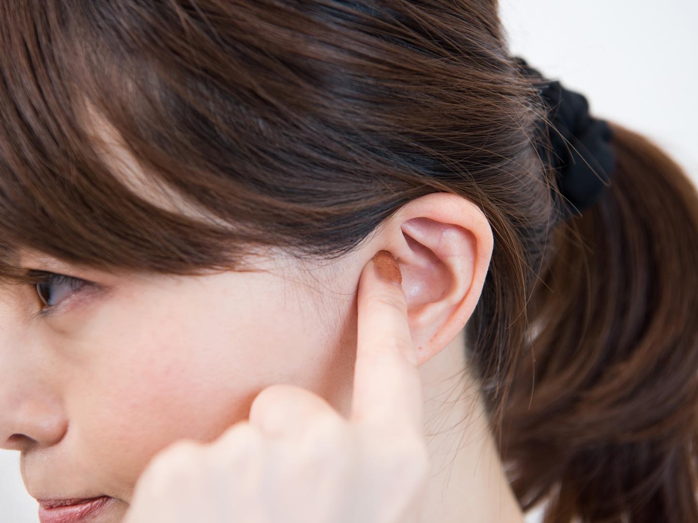 耳ツボ「飢点」のマッサージをしている女性