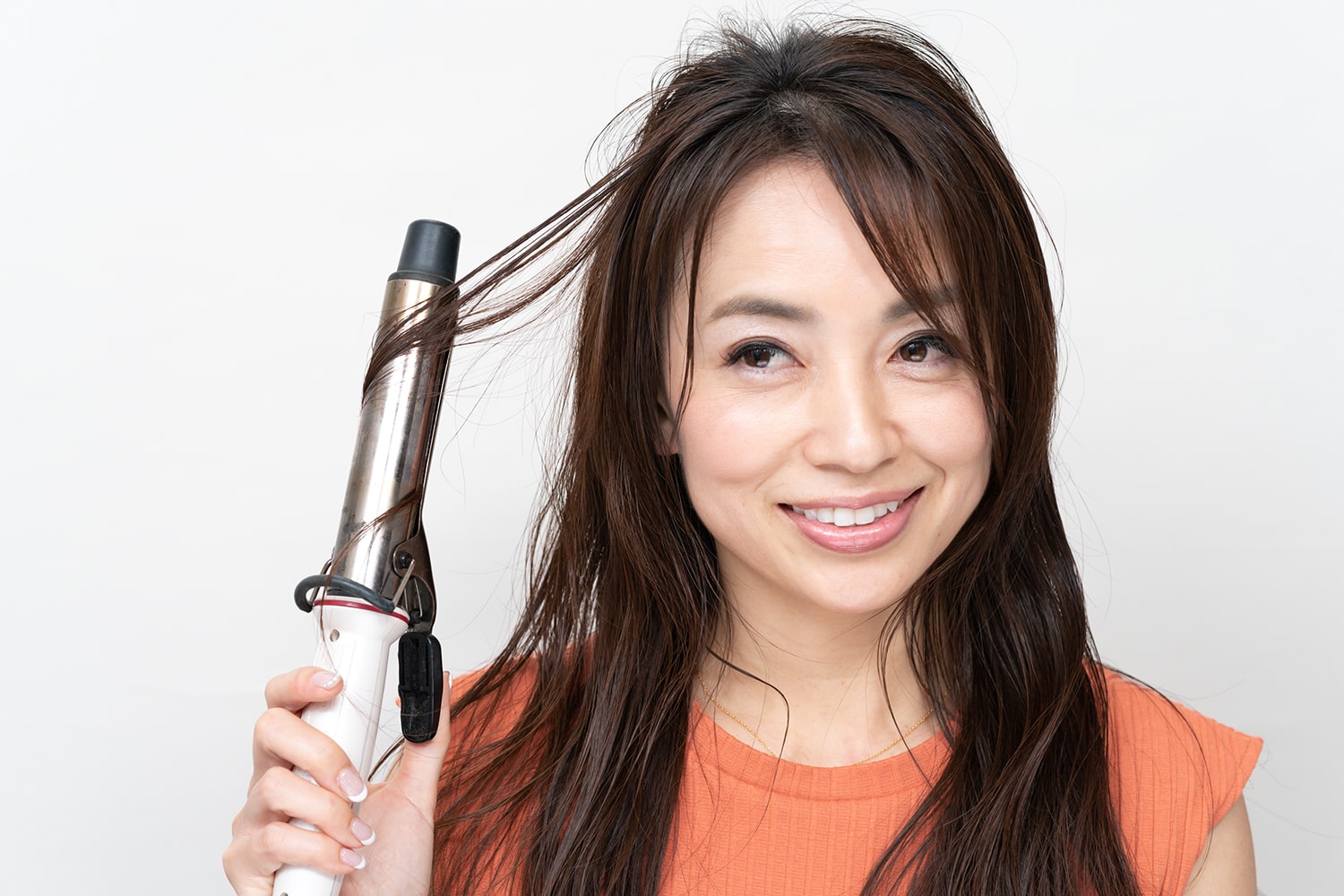 表面の毛束を爪でつまんで引き出し、コテで中間を巻く。ランダムに毛束を取って巻くと自然な仕上がりになる。