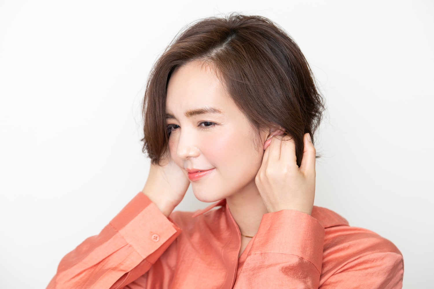 オイルクリームを手のひらにのばし、耳うしろをメインに髪の内側になじませる。手のひらに残った分を、全体になじませて整える。