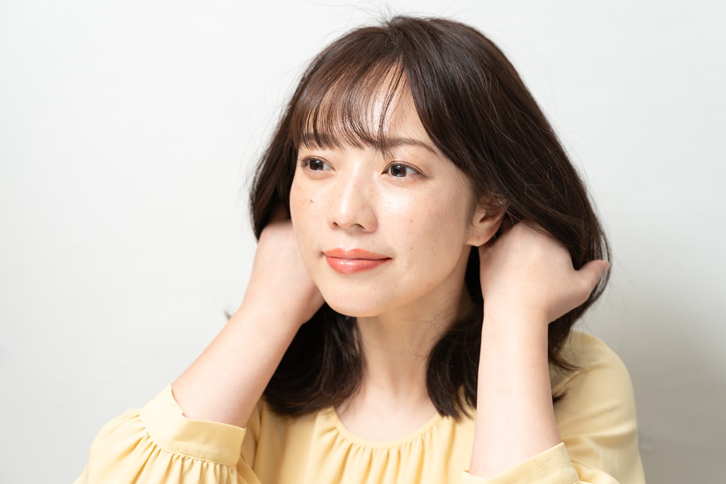 両手のひらにクリームを広げ、耳の後ろあたりの髪になじませる。