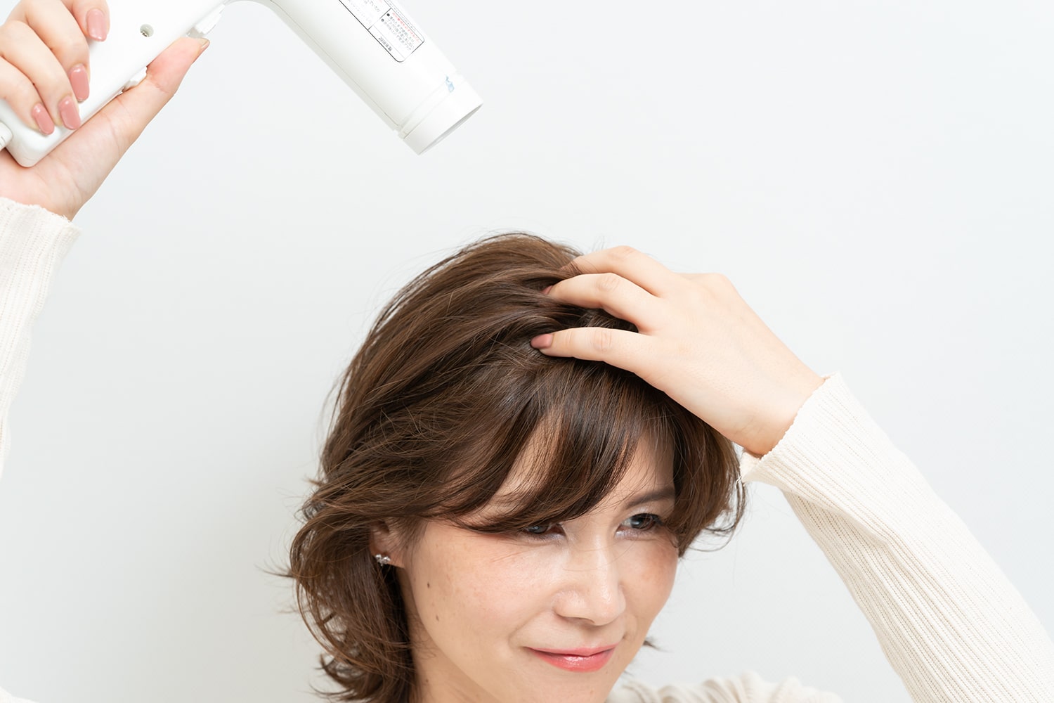頭頂部を指のひらでこすりながらドライヤーの熱を当てる。