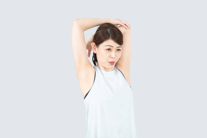 右手で左肘をつかんで、深呼吸しながらストレッチを