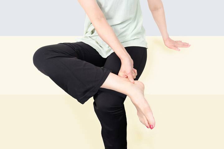 椅子に座り、右足を左の太ももに乗せてアキレス腱あたりをつかむ