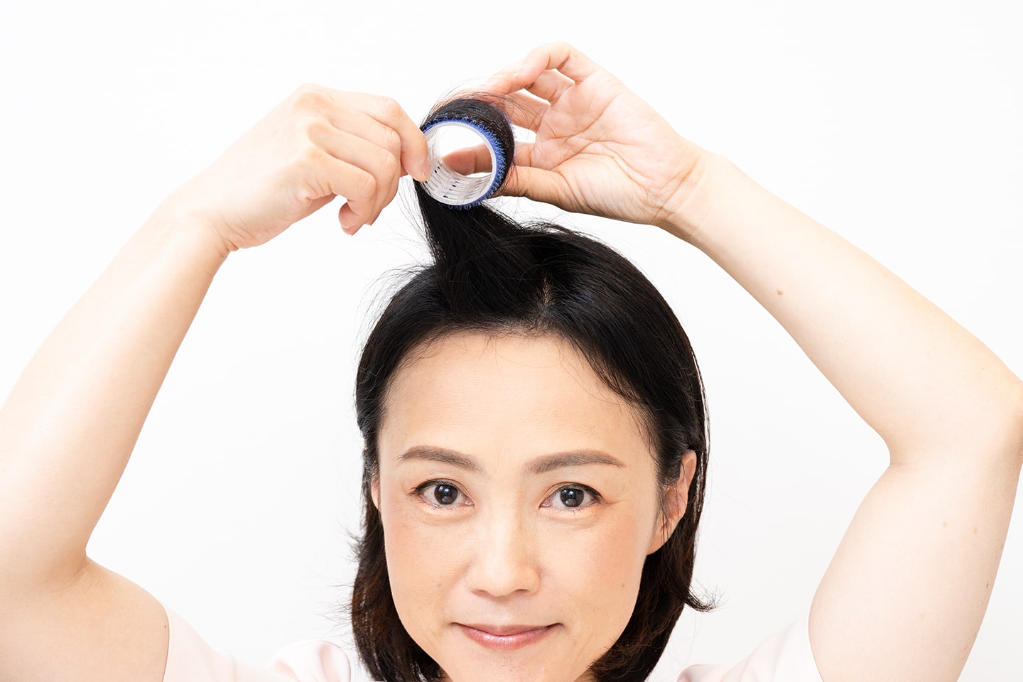 分け目側に毛束を引っ張りながら毛先から根元までカーラーで巻く。