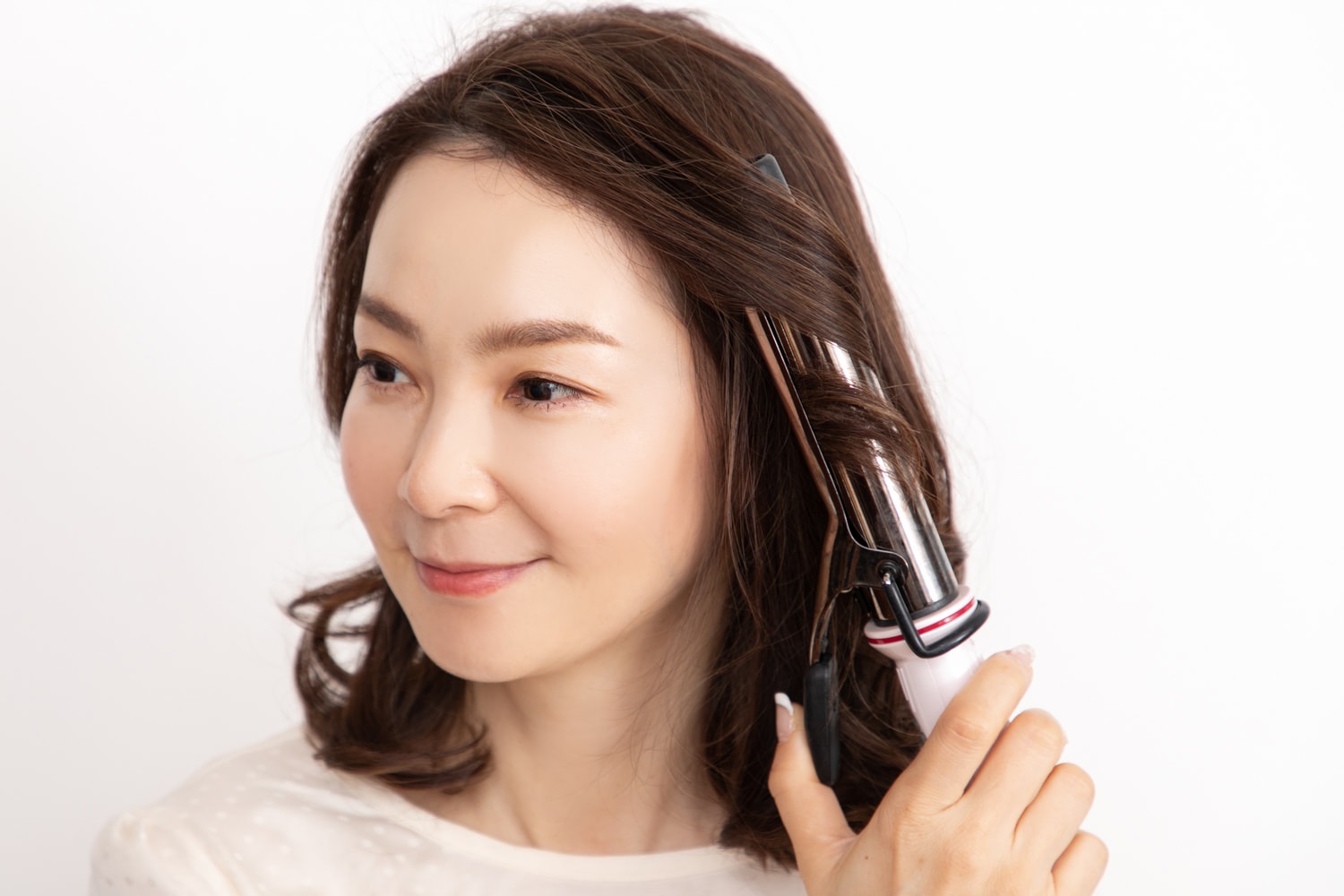 同じヘアアイロンで、顔周りとハチ上の毛束を毛先から1回転半外巻きに。