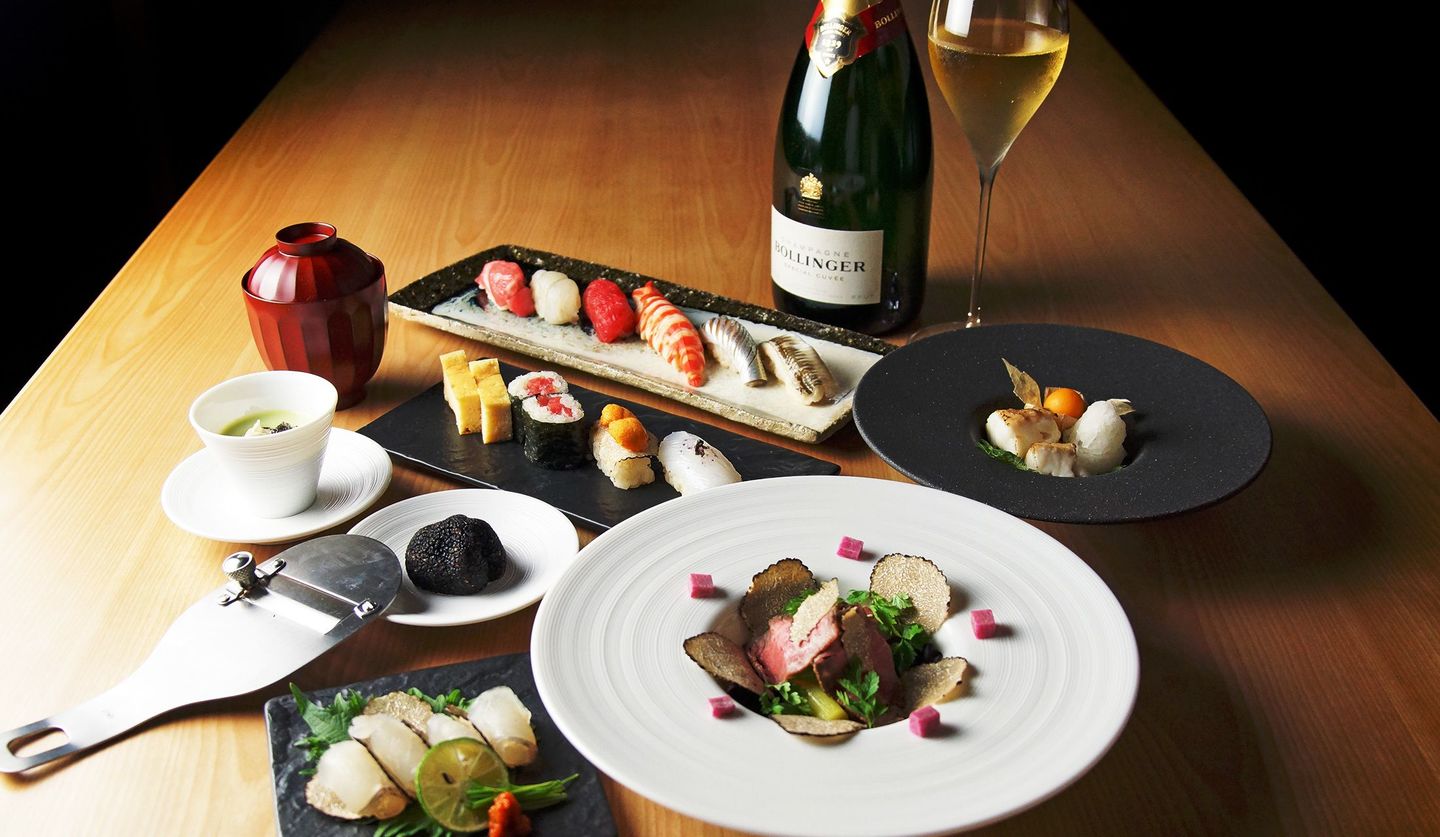 トリュフ料理と鮨、シャンパンがテーブルの上に載っている写真