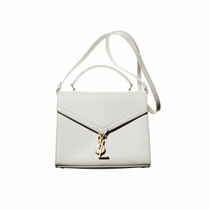 均整のとれたスクエアフォルムに、底のマチは11.5cmと適度に広めで安定感がありながら、すっきりスマートな横顔。肩がけしたときも、ボディーラインになじみやすい。ロゴのクラスプは、飾りであるだけでなく、クロージャーも兼ねています。トップハンドルの場合、簡単に開閉できるのはうれしいもの。開くと中はボルドーのレザーでシックに。2コンパートメントで仕分けしやすく、中と外にひとつずつポケット付きと機能的にも充実。幾何学的なデザインのロゴが映える、上品なオフホワイトのバッグ『モノグラム・サンローラン カサンドラ』［縦20×横24.5×マチ11.5cm］￥249,000（イヴ・サンローラン〈サンローラン バイ アンソニー・ヴァカレロ〉）