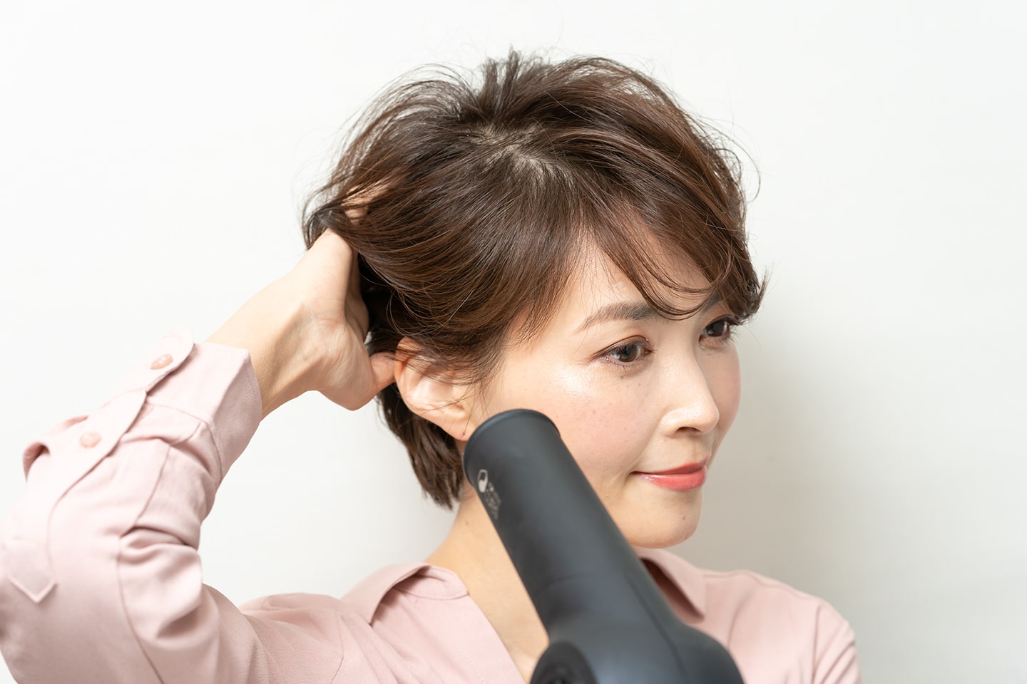 手ぐしで後ろへとかしながらドライヤーをあてる。