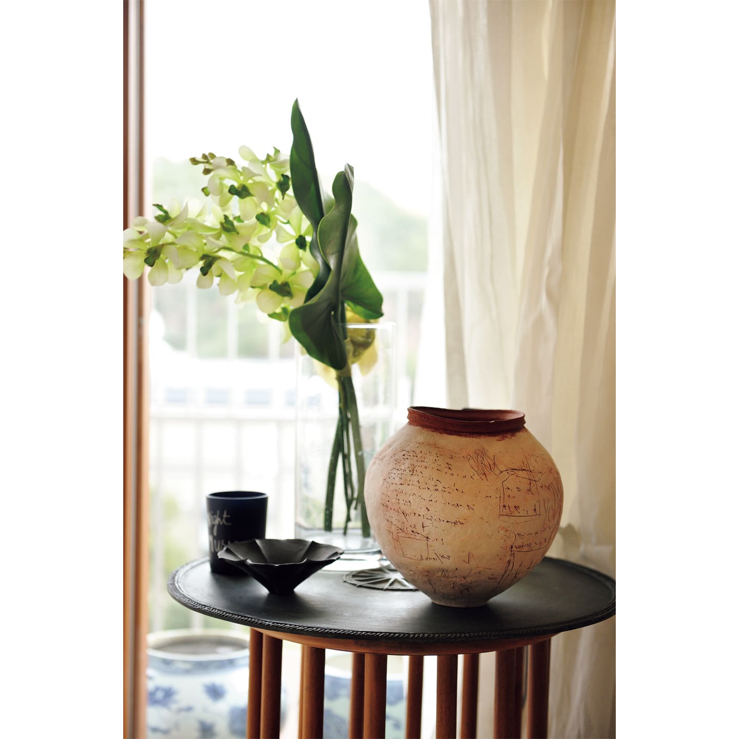 花器と手前の花皿は陶芸家・内田鋼一氏の作品。サイドテーブルは、タイ・プーケットのリゾート「アマンプリ」に滞在中、プールサイドで見つけて気に入り、交渉して同じものを購入。