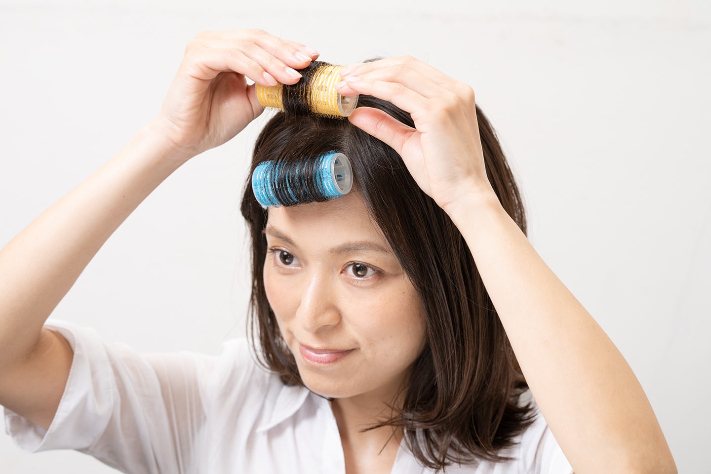 根元を立ち上げるように毛束を持ち上げながら内巻きにカーラーを巻く。