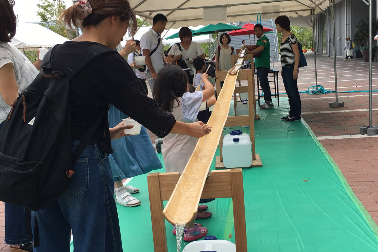 街のイベントで流している様子。竹のレールを複数本重ねれば、長いレールができあがります(提供:世界流しそうめん協会)