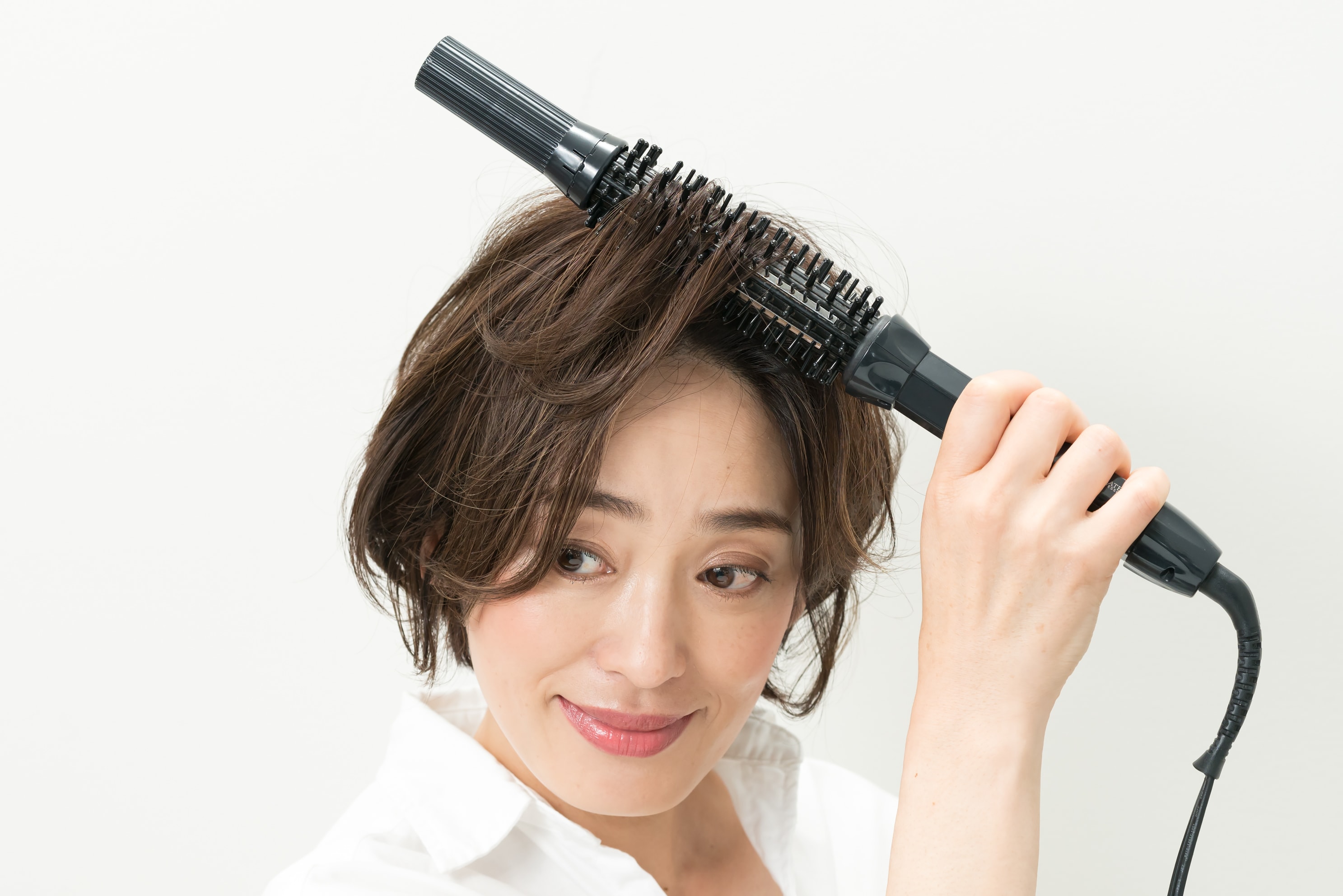 髪の根元を立ち上げるようにアイロンを内側から入れ、大きな円を描くように内巻きにします。両サイドとバックも同様に。
