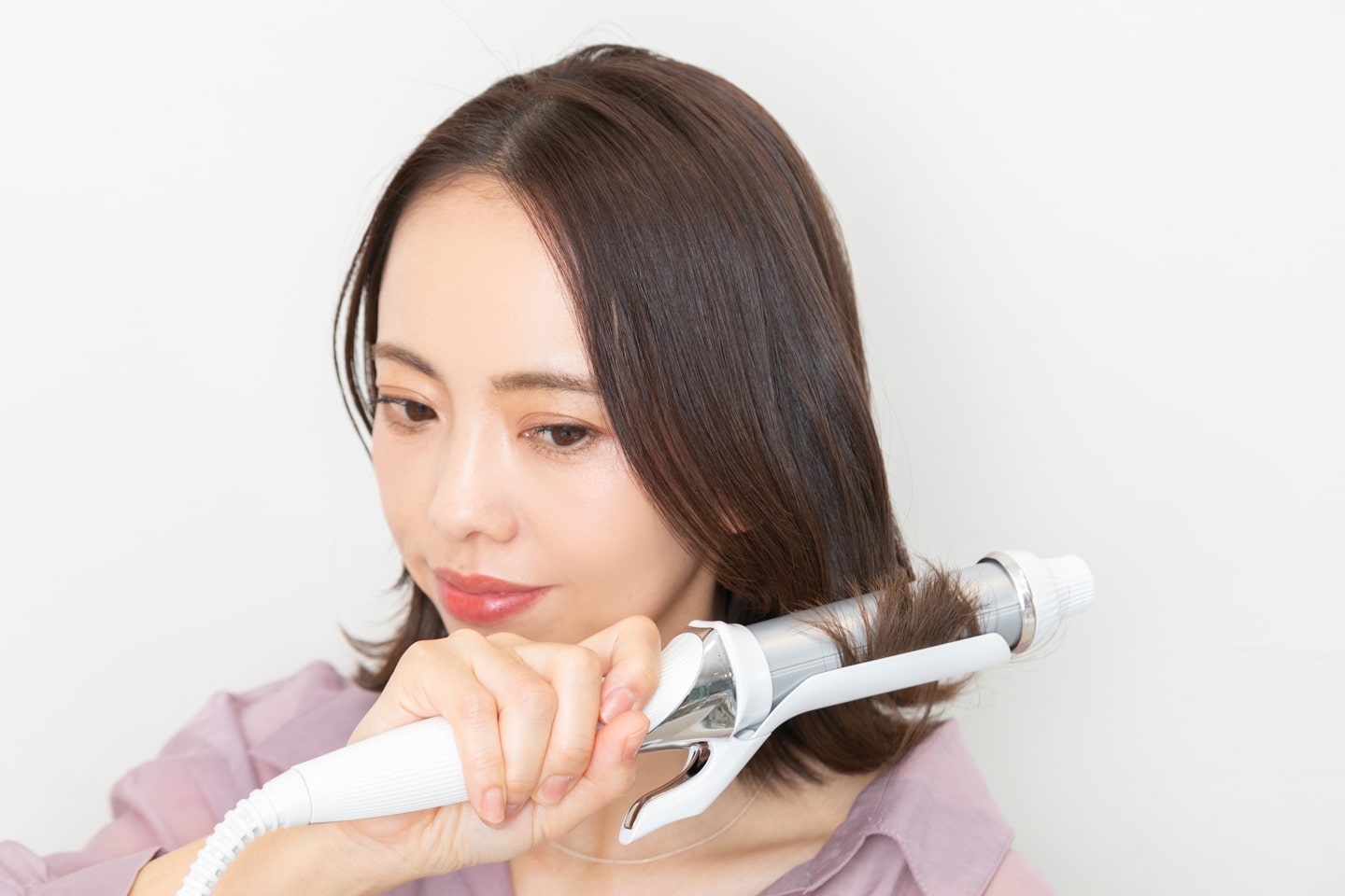 32mmのヘアアイロンで、全体の毛先から一回転巻いて外ハネにする。