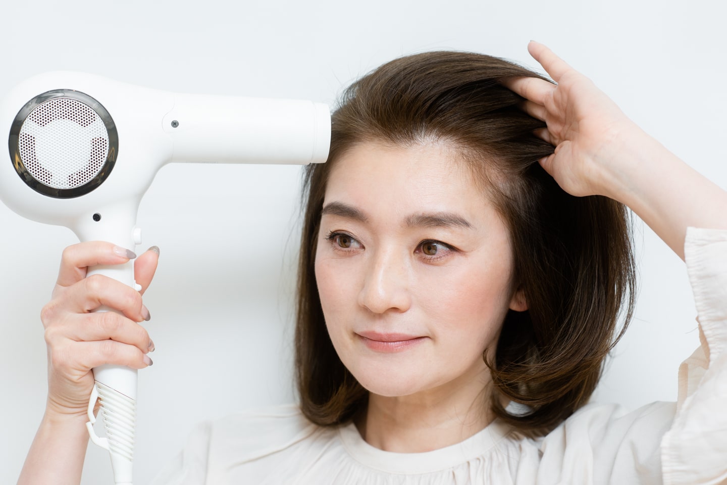 分け目と反対に向かってドライヤーの風を当て、根元を起こしながら乾かす。