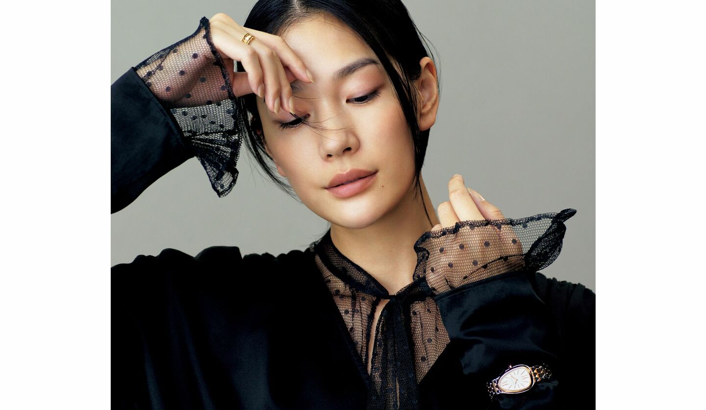 ボウタイブラウスにVネックブラウスを重ねたモデルの大塚まゆかさん