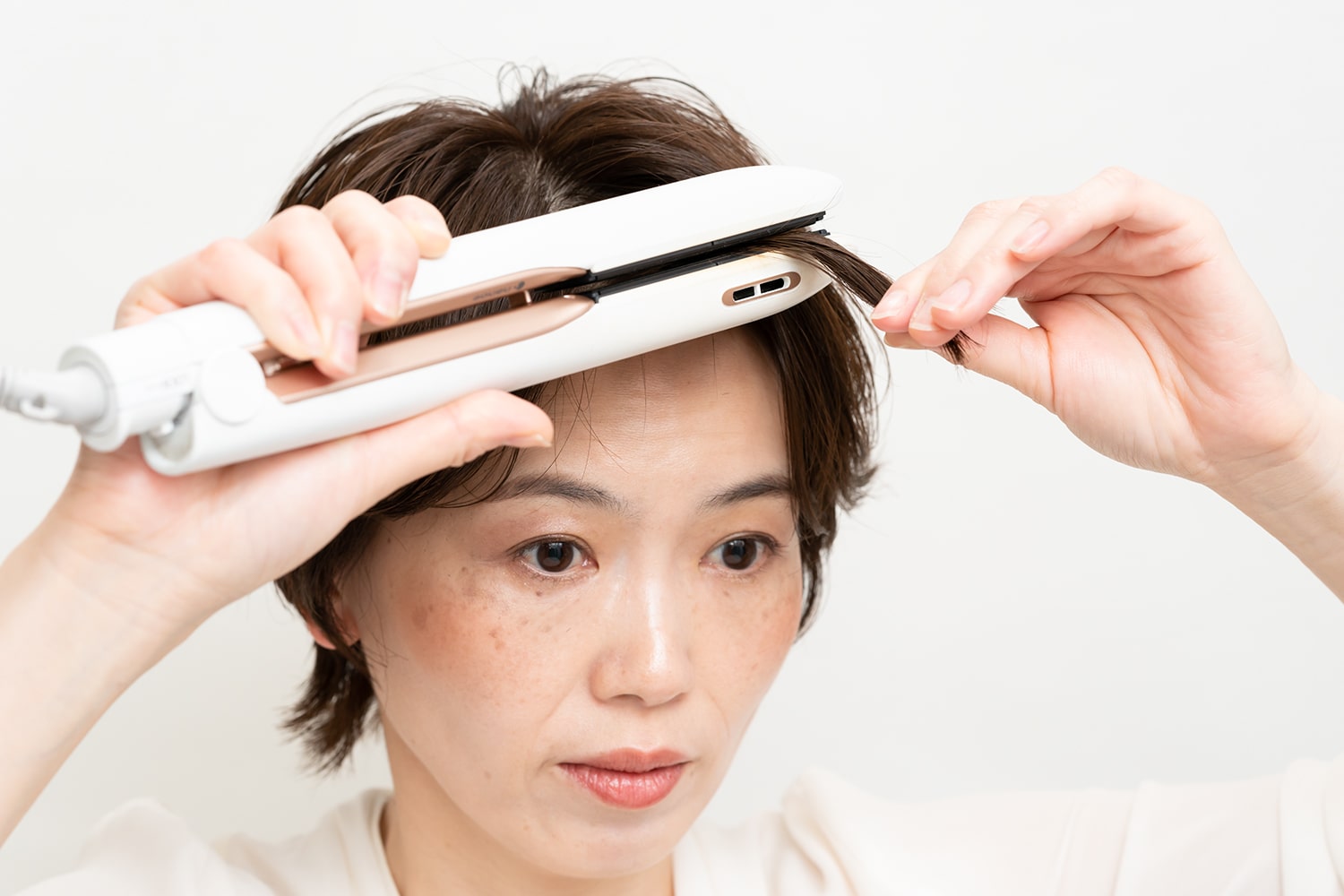 毛束の中間から毛先にかけて滑らせるようにアイロンをかけるのがコツ。