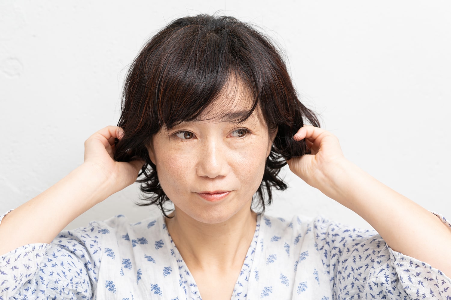 両手のひらにワックスを広げたら、毛先を握るようにしてなじませる。