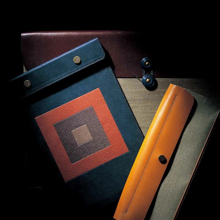 奥／伸縮性が少なく丈夫な牛革×プレスコットンでつくられた、スタイリシュなA４サイズの封筒形ケース。薄型のノートパソコン入れとしても重宝。［縦26.5×横38×マチ５㎝］¥26,500・左／レザーのモザイク模様が印象的なA５サイズのスナップパッドは、牛革×ピッグスキンを採用。［縦23×横16㎝］¥24,000・右／ツールボックスは、かさ張る文具もすっぽり収納。［縦9.3×横21.3×マチ３㎝］¥17,000（ポスタルコ）